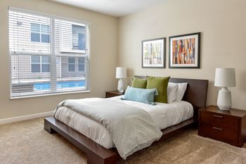 A bedroom with a large bed and two lamps.